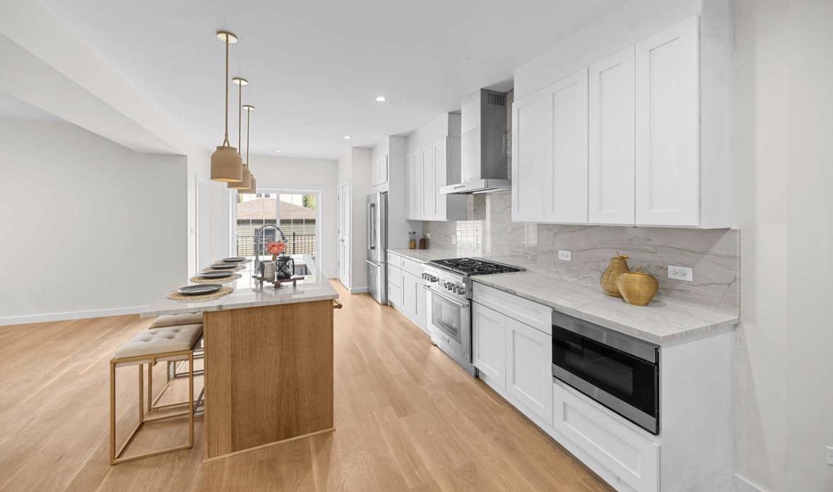 White kitchen with brass pendants and marble counters